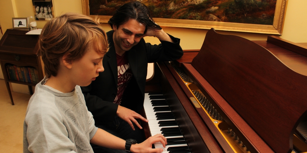 Phil listening as a young pupil plays a grand piano.